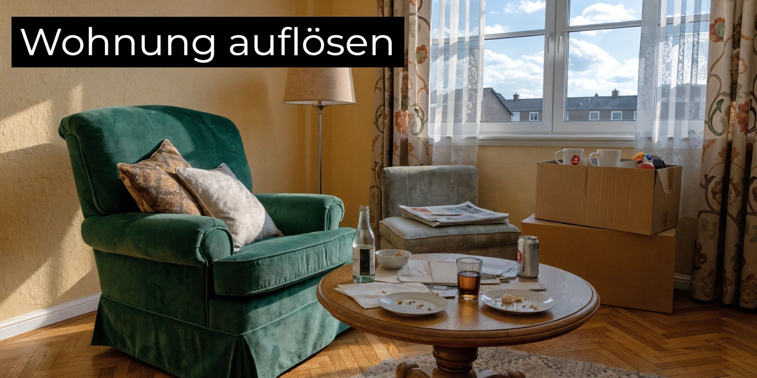 Ein gemütlicher grüner Sessel und ein Kaffeetisch in einem Wohnzimmer, das für eine Wohnungsauflösung vorbereitet wurde.