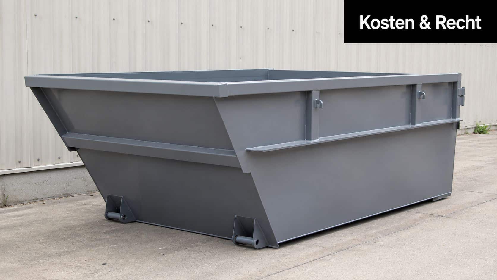 Ein großer, grauer Metallcontainer steht auf einem befestigten Platz vor einer industriellen Wellblechwand für Entsorgungszwecke bereit.